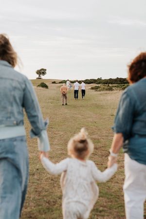 People walking together across an open field at golden hour with a lone tree visible in the distance.
