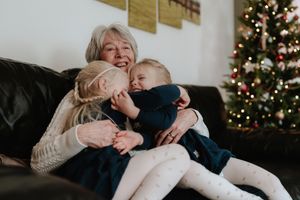 Joyful holiday moment shared between family members on a couch with a decorated Christmas tree in the background.