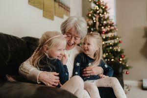 Candid family moment of playful interaction on sofa with Christmas decorations visible in living room.