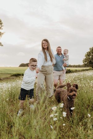 Family and their dogs posing together in a blooming wildflower meadow.