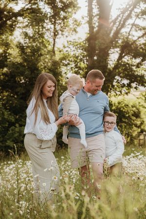 Family walking together through tall grass and wildflowers during golden hour.