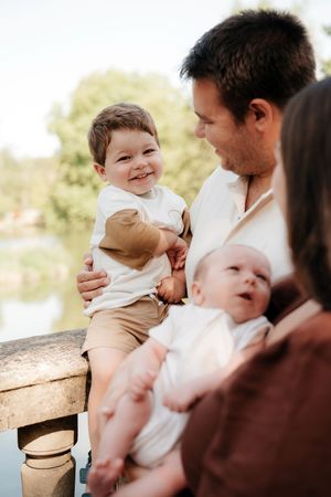 A series of candid outdoor family moments showing tender interactions between parent and baby on a wooden bench.