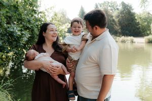 A family shares joyful moments together by a serene pond on a sunny afternoon.