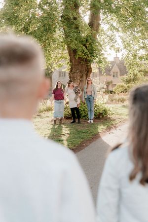 A family gathering outdoors under trees captured in a series of connected lifestyle photos with soft natural lighting.