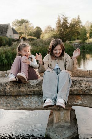 Two people sit together on a stone wall by a pond, sharing joyful moments and laughter in a series of candid shots.