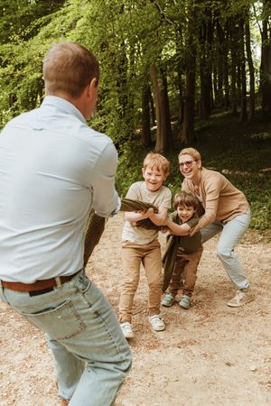 Playful family chase sequence on a wooded trail during a fun outdoor adventure.