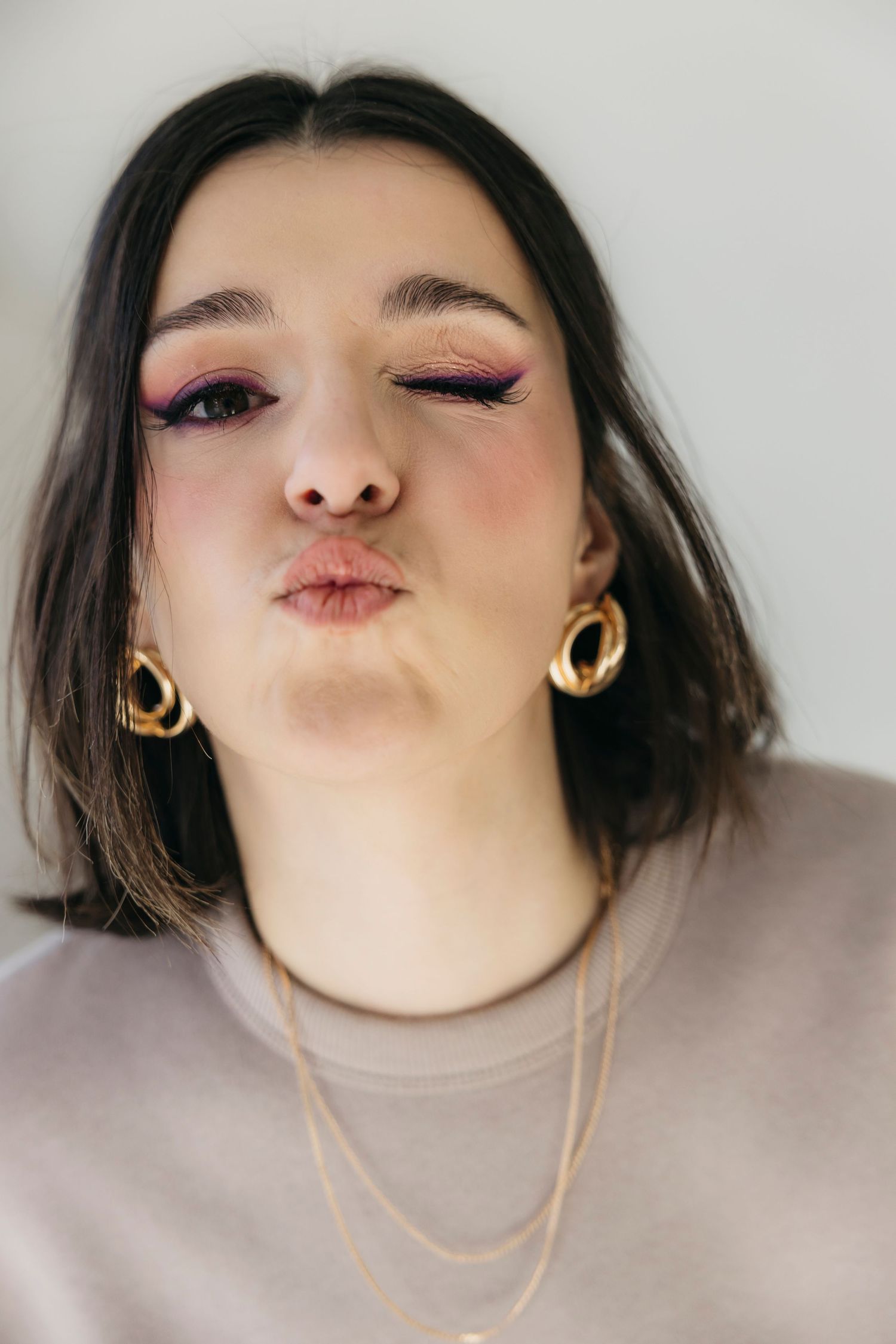 Close-up of makeup look featuring pink eyeshadow and gold hoop earrings.