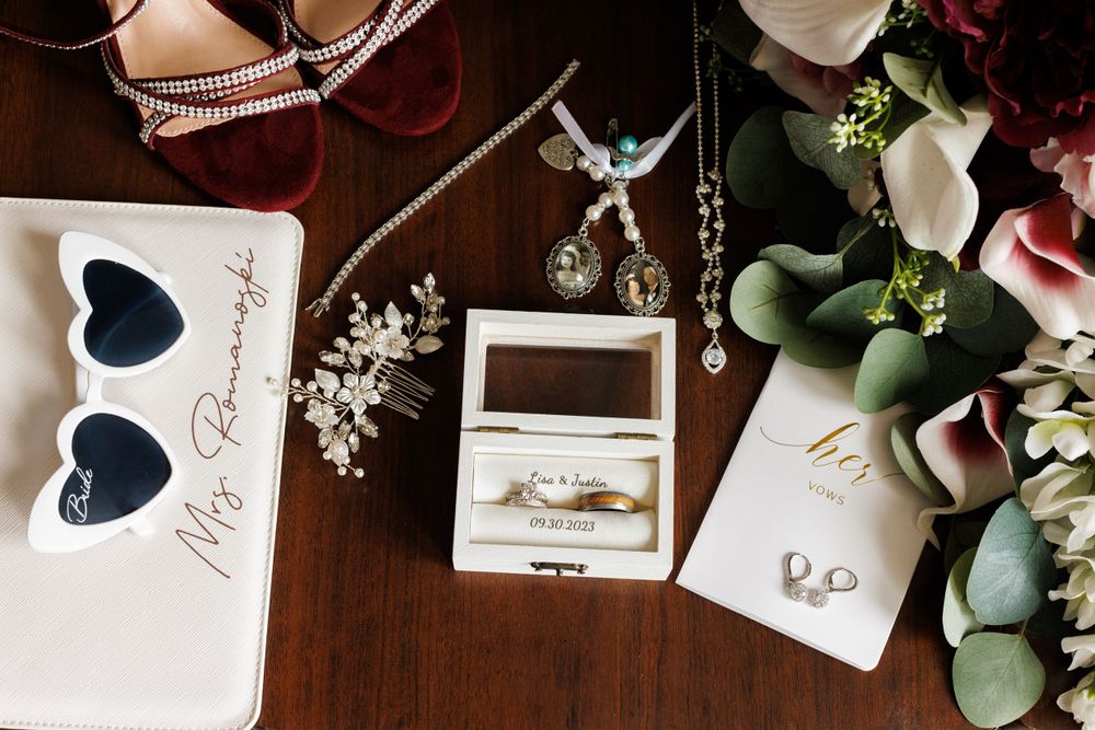 Flat lay of wedding details including rings, jewelry, bouquet, and bridal accessories.