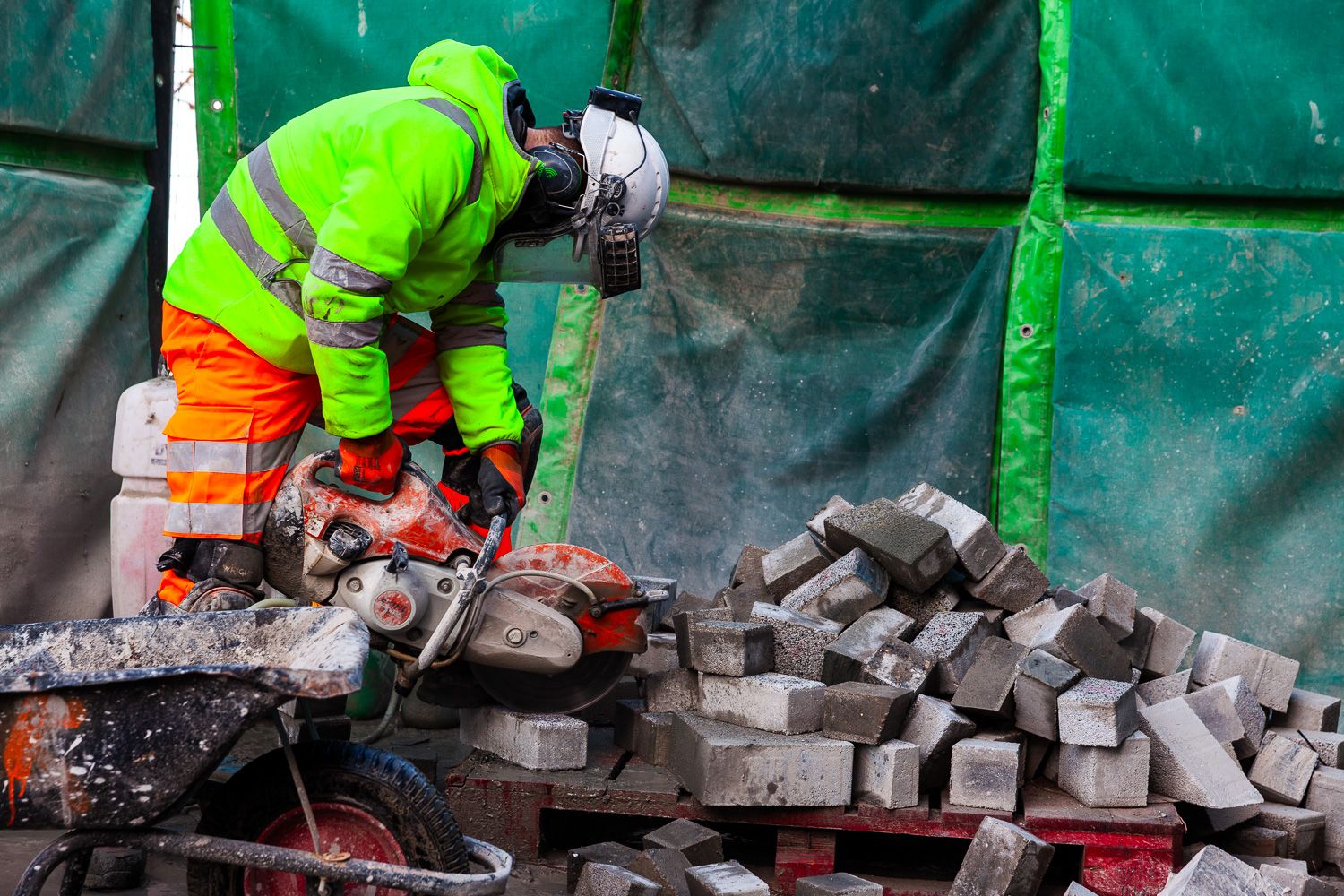Construction photograph of worker cutting blocks with angle grinder
