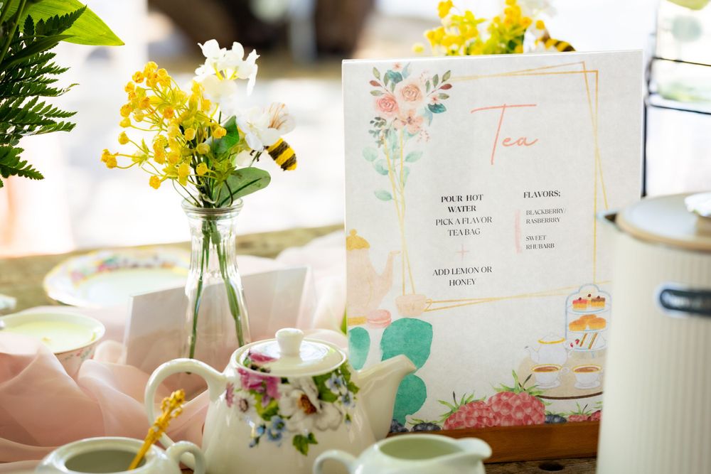 Delicate floral menu card displayed with yellow flowers and vintage teacups on a light table setting.