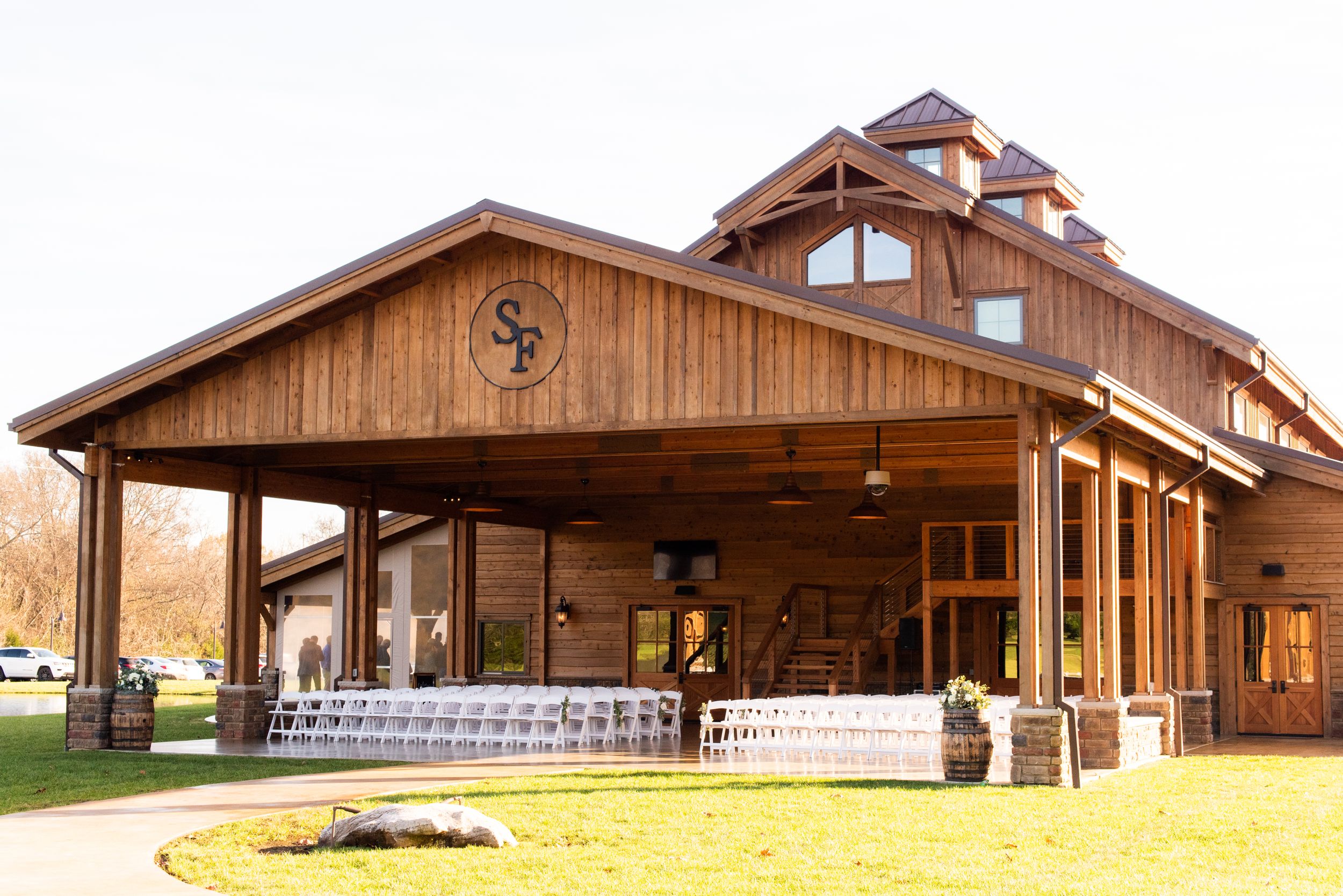 Rustic wooden barn venue with covered porch and architectural details in warm sunlight.