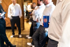 Groomsmen in white dress shirts and dark pants stand together during wedding preparations.