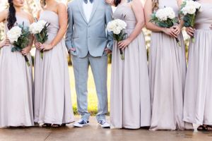 Wedding party lined up showing grey suit and blush bridesmaid dresses with white bouquets.