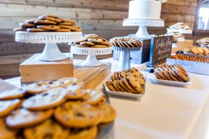 Wedding dessert table with cookies and cakes displayed on white cake stands.