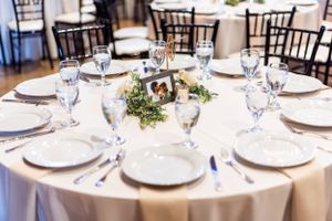Elegant table setting at wedding reception with white linens and floral centerpiece.
