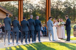 Wedding ceremony with groomsmen in navy suits and couple exchanging vows.