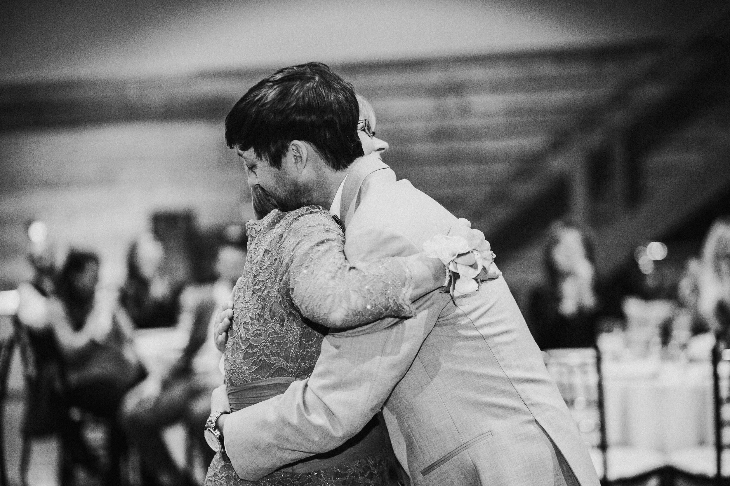 Black and white photo of couple embracing during wedding reception.