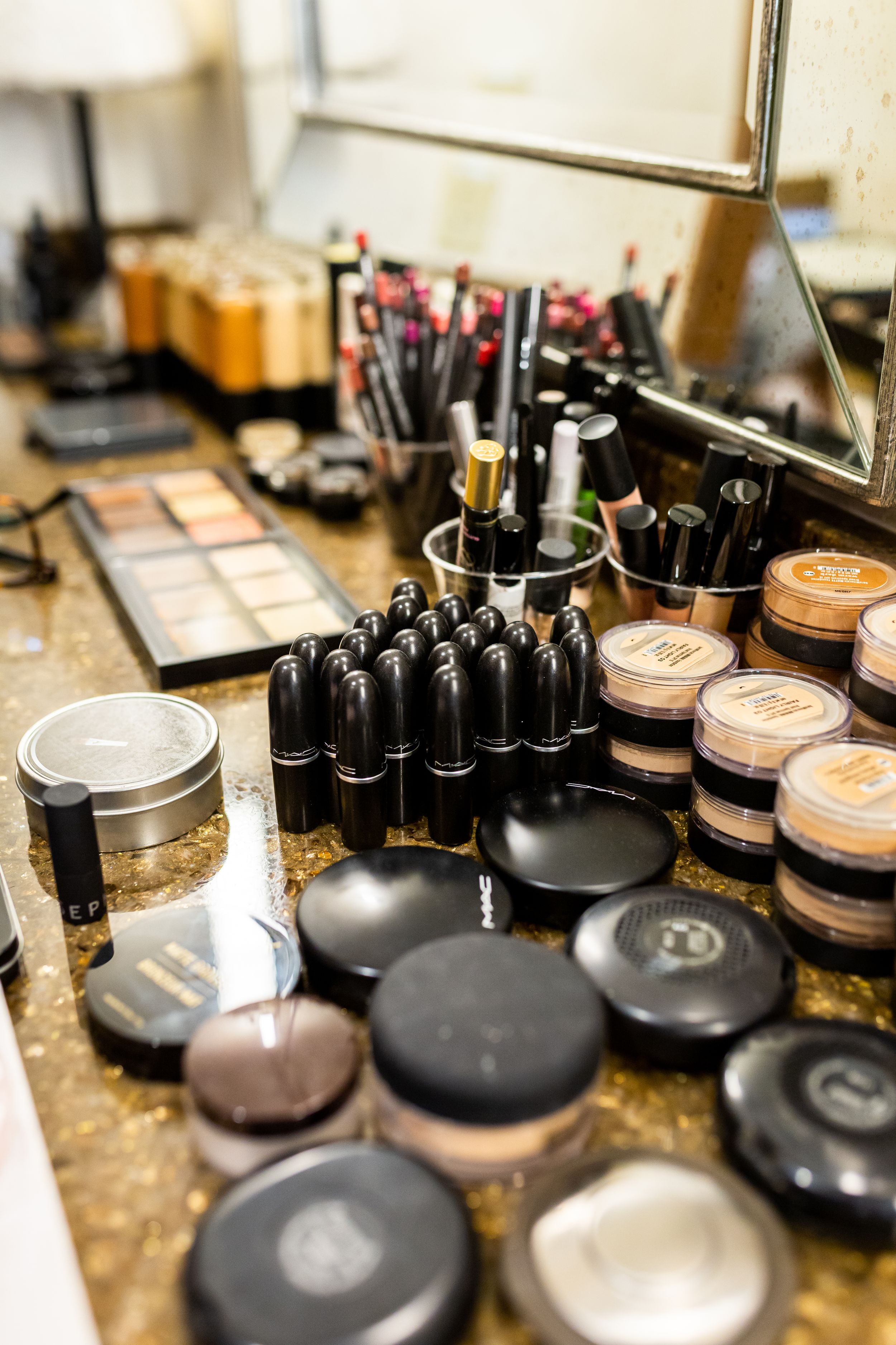 Collection of makeup products including lipsticks and cosmetic containers arranged on a vanity counter.