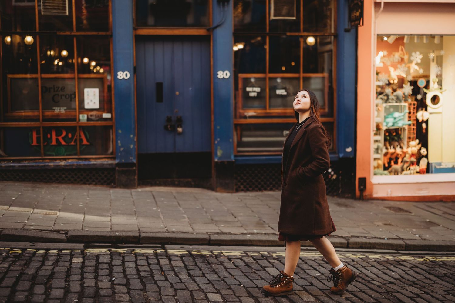 A panoramic view of a historic cobblestone street lined with charming storefronts and shops at dusk.