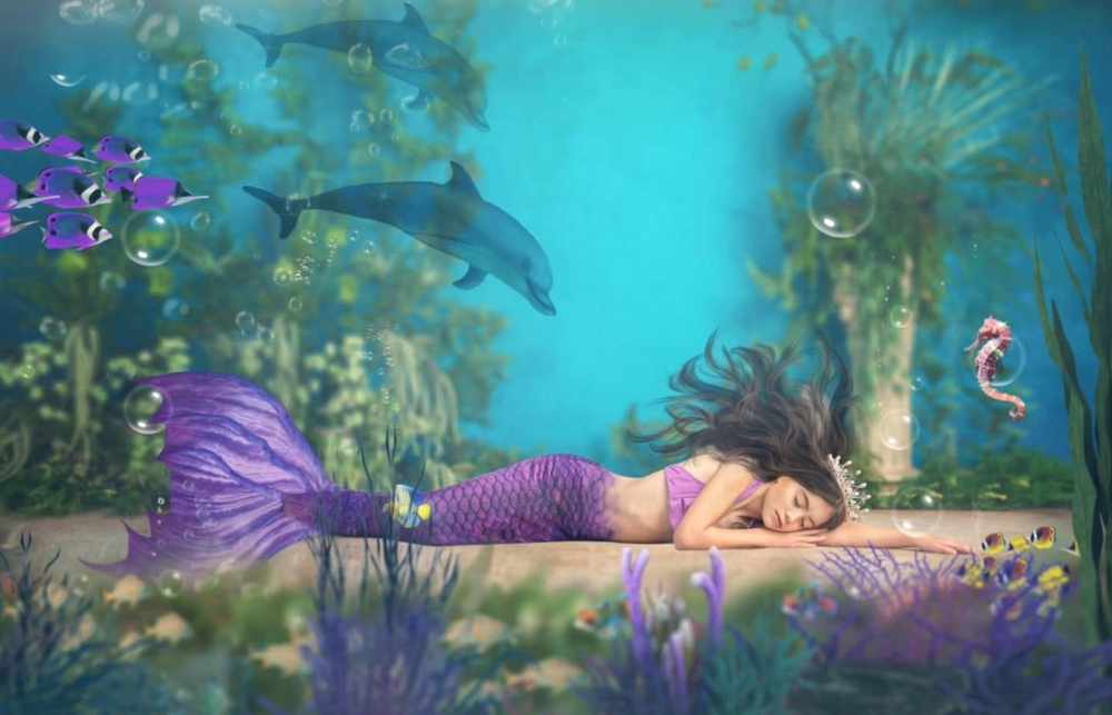 A sleeping mermaid with purple tail rests underwater surrounded by dolphins, seahorses, and colorful fish in a fantasy ocean scene.
