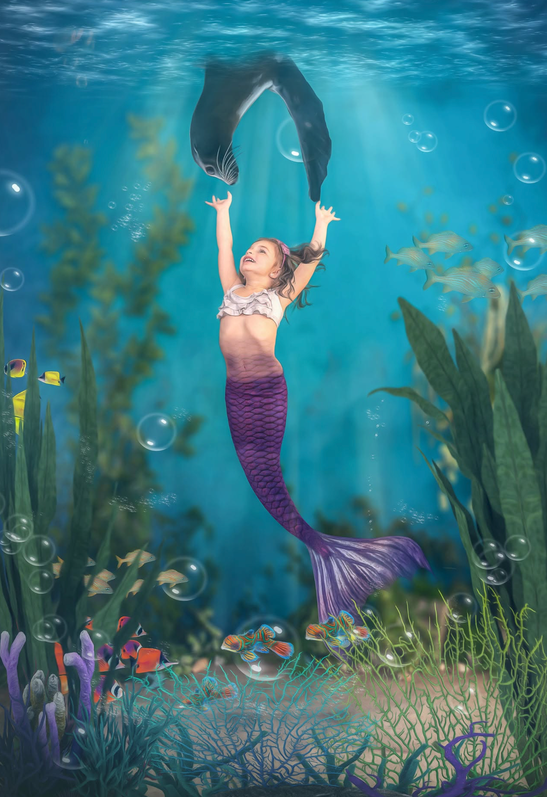 A young girl dressed as a mermaid with a purple tail poses underwater surrounded by colorful fish and bubbles.
