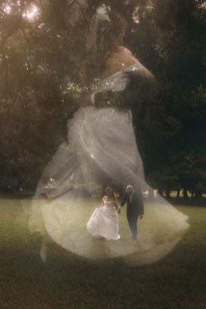 Dreamy double exposure of bride in flowing white gown and groom walking through sunlit garden.