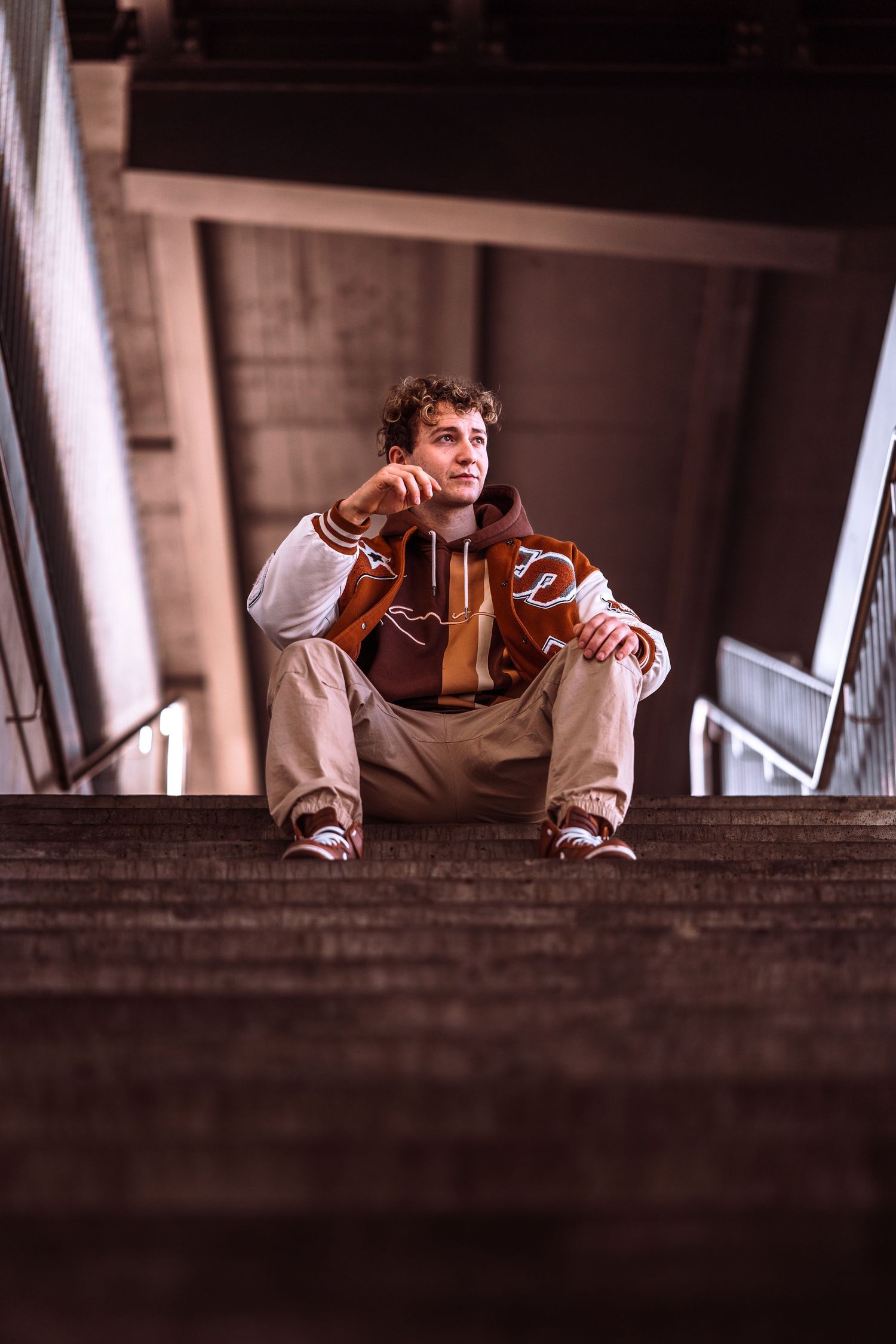 A person in casual wear sits on concrete steps in an urban setting.