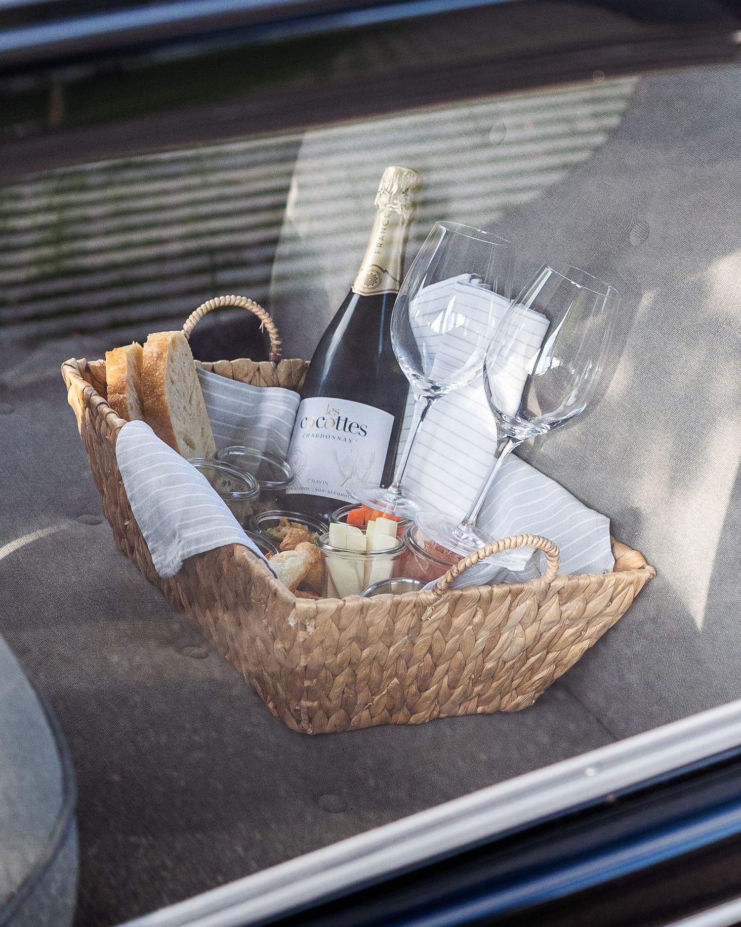 Elegant wedding gift basket with champagne bottle and wine glasses in woven container.