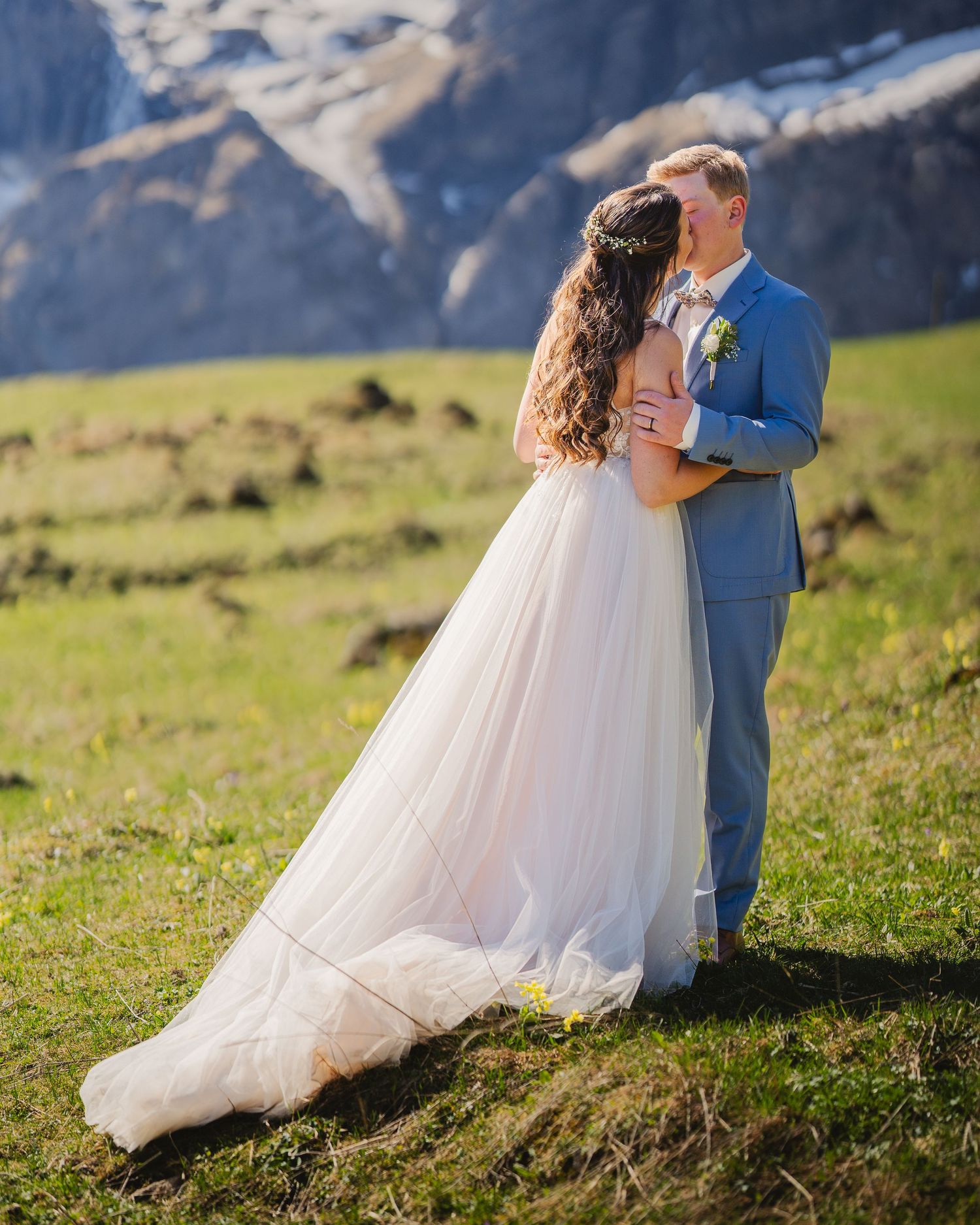 A romantic wedding portrait set against majestic mountain scenery with sweeping green hillsides.