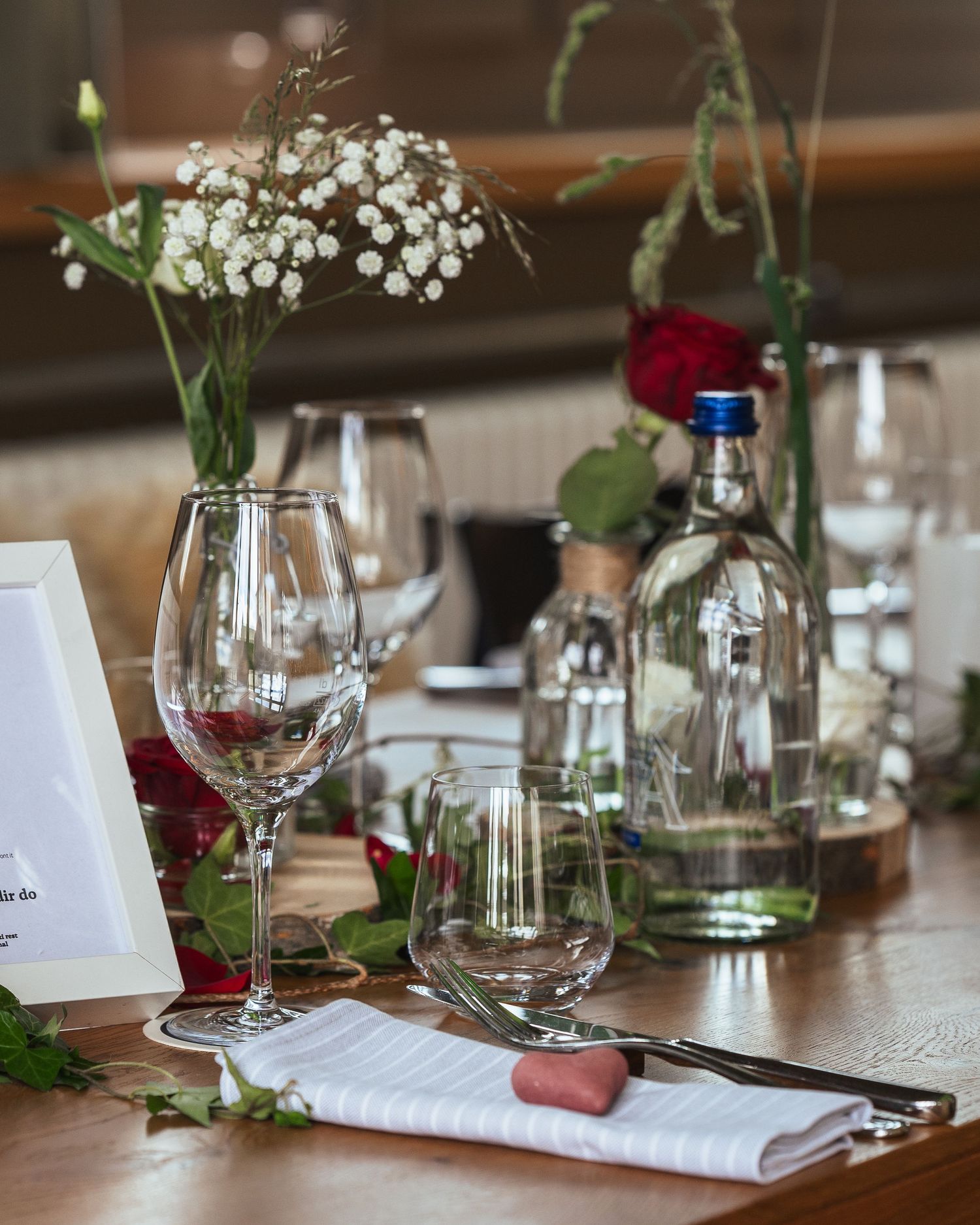 An elegant table setting with wine glasses, baby's breath flowers, and place settings for a romantic dinner.