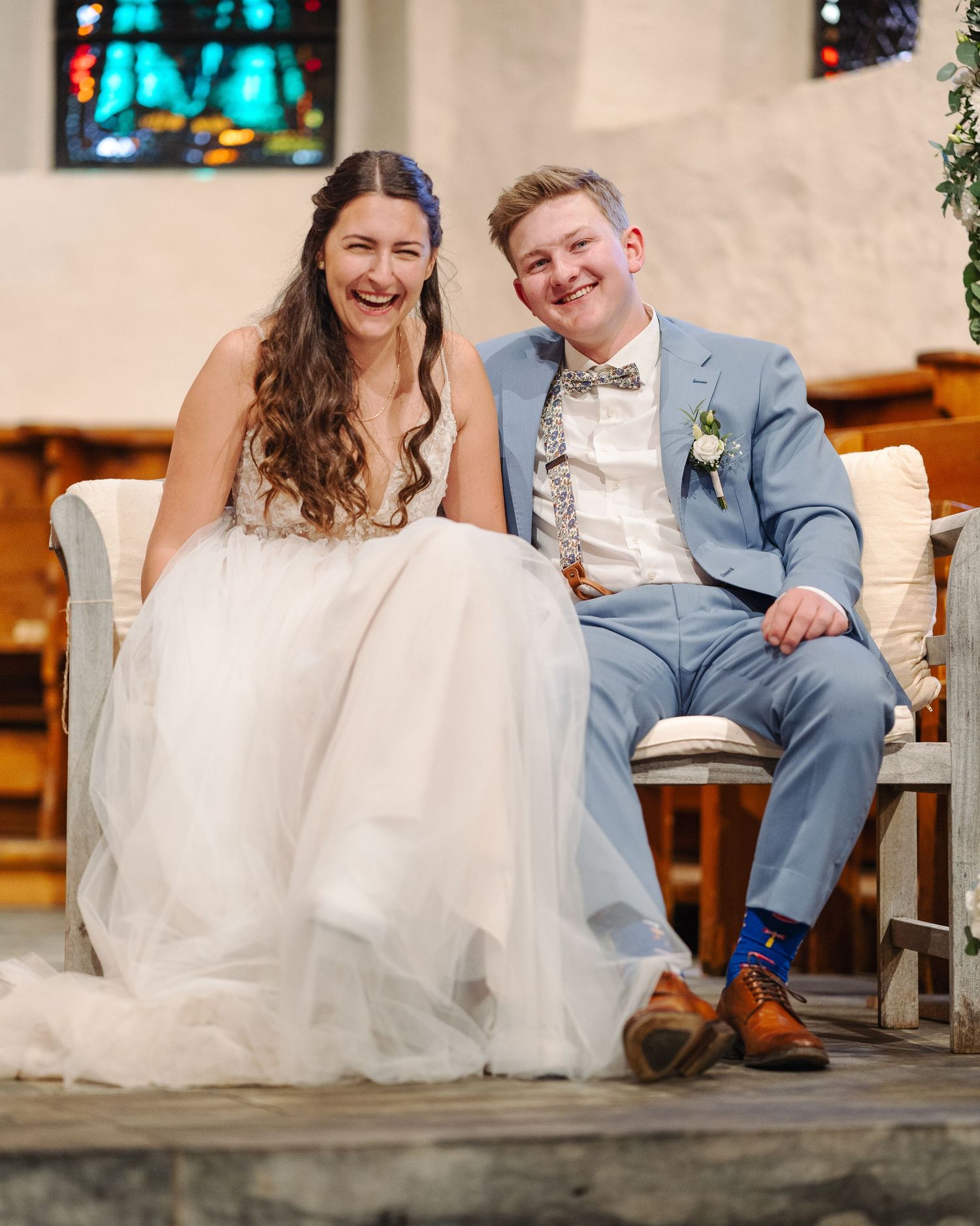 A joyful wedding moment captured inside a church with stained glass windows in the background.