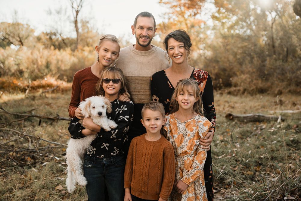 A joyful family photo session in a rustic autumn field with warm lighting and fall foliage.