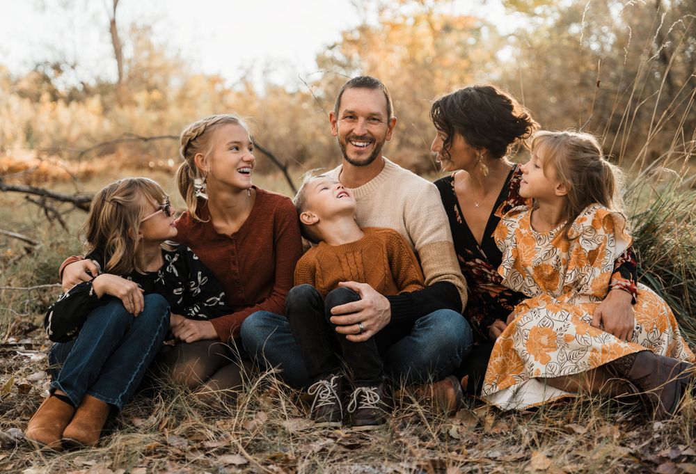 Family lying down together on grass during outdoor fall photo session.