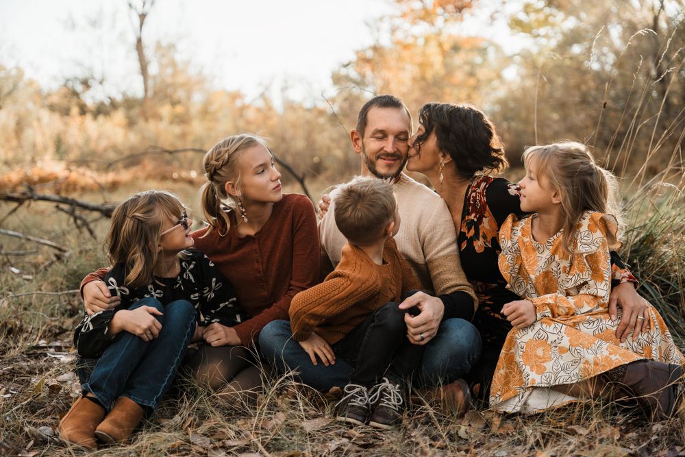 Playful family portrait series in autumn field with casual poses.