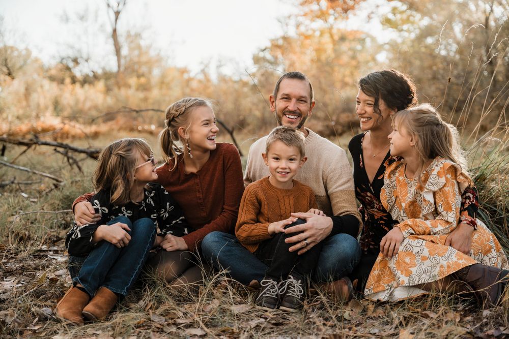 Family laying together on ground during golden hour autumn photoshoot.