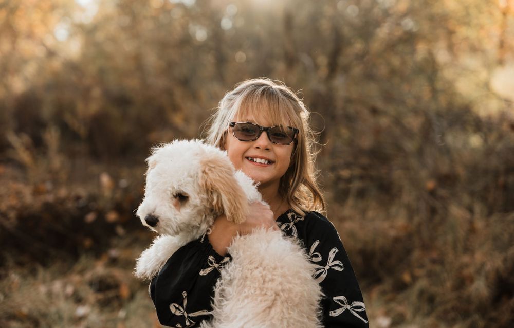 Small white dog and family members during fall outdoor photoshoot.