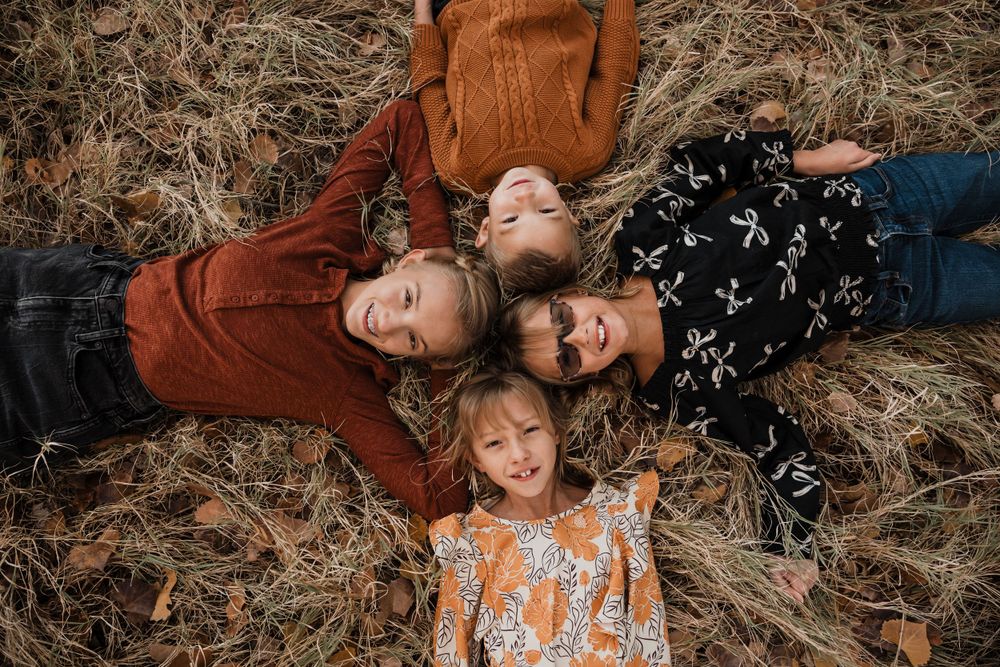 Family members relaxing on ground during casual autumn photo session.