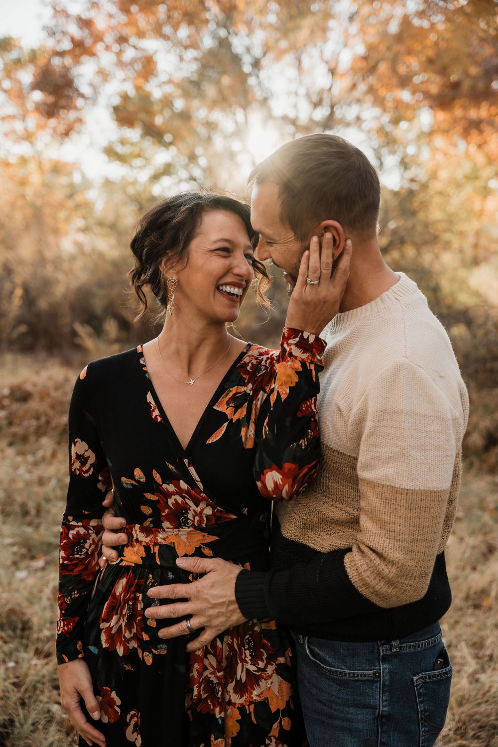 A couple shares intimate and joyful moments in an autumn outdoor setting during a photoshoot.