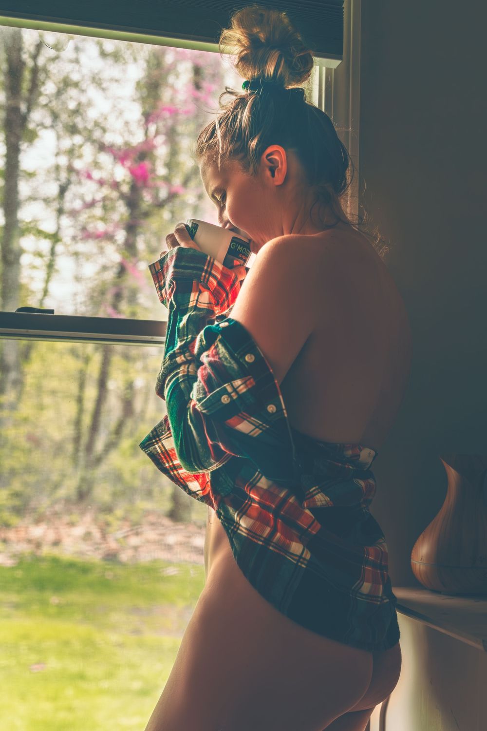 A person wearing a plaid dress sits by a sunlit window in a series of four connected photographs.