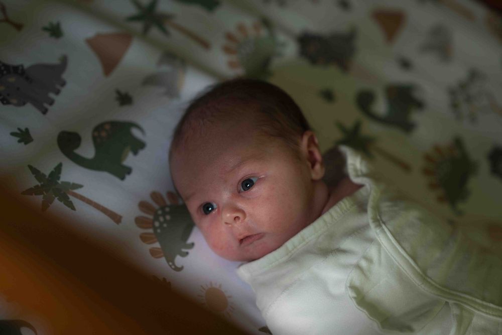 A series of close-up shots showing a sleeping infant in white clothing against a patterned background.