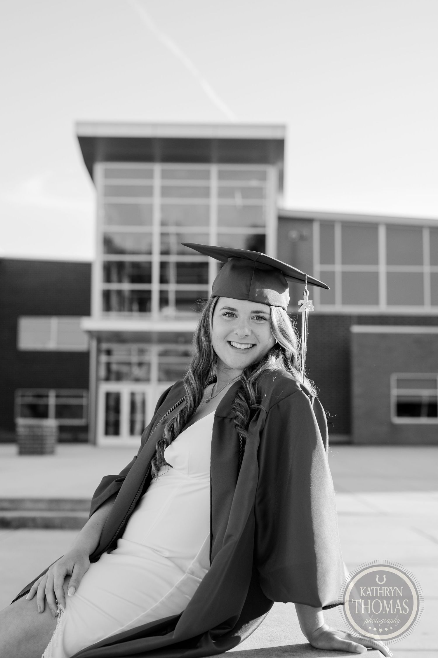 Black and white portrait of graduate outside modern school building.