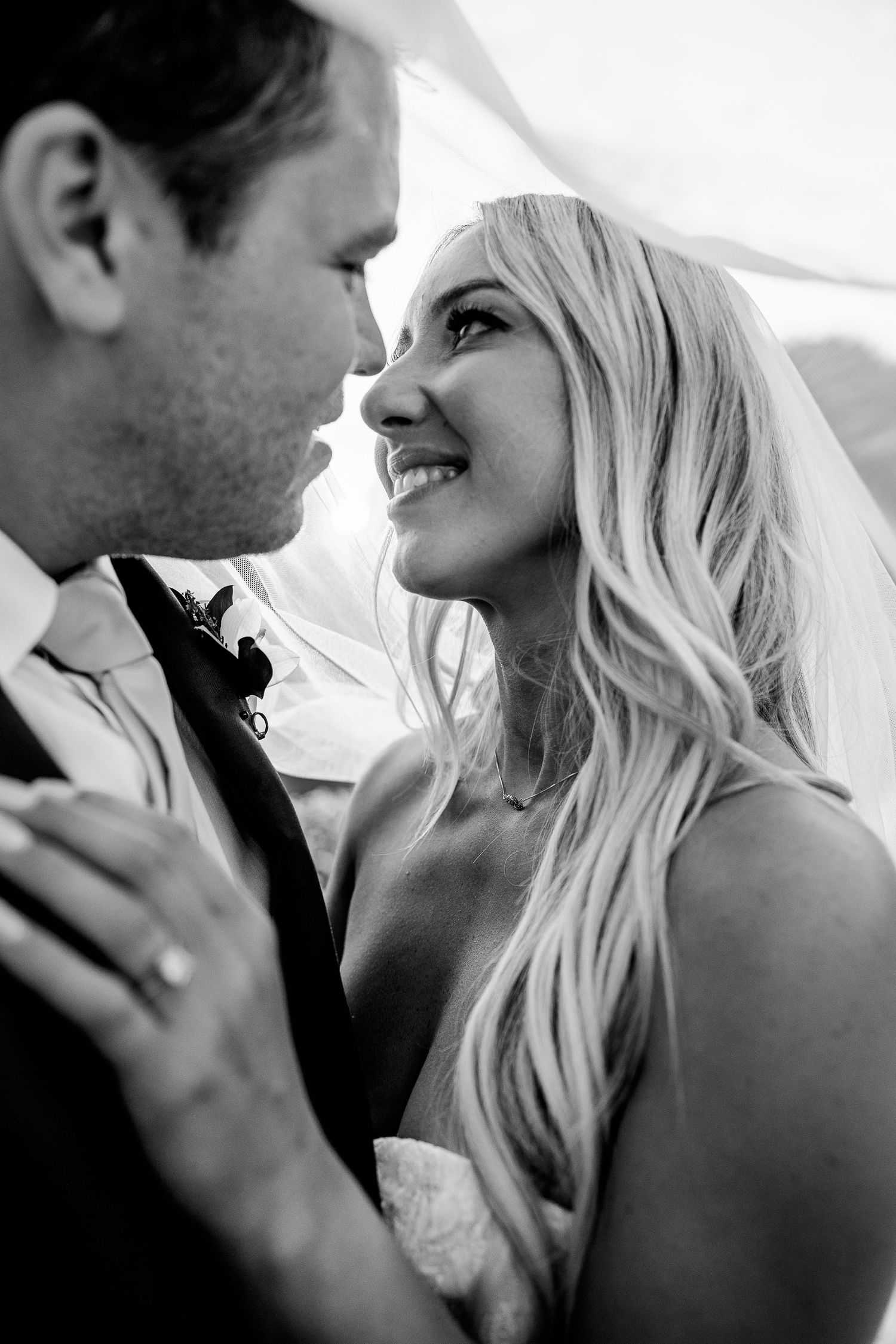 A couple shares a joyful moment while cutting their elegant white wedding cake.
