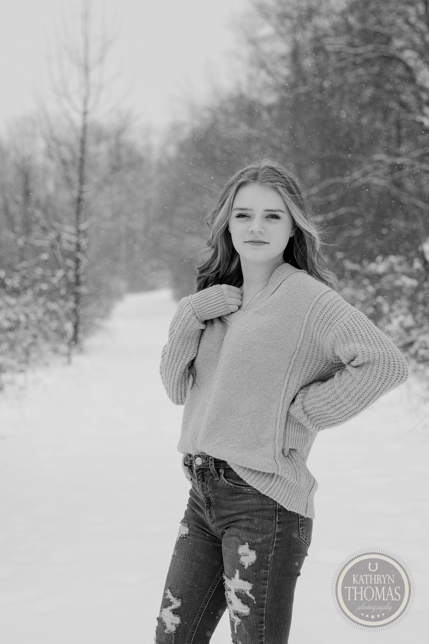 Black and white portrait of person in knit sweater on snowy path.