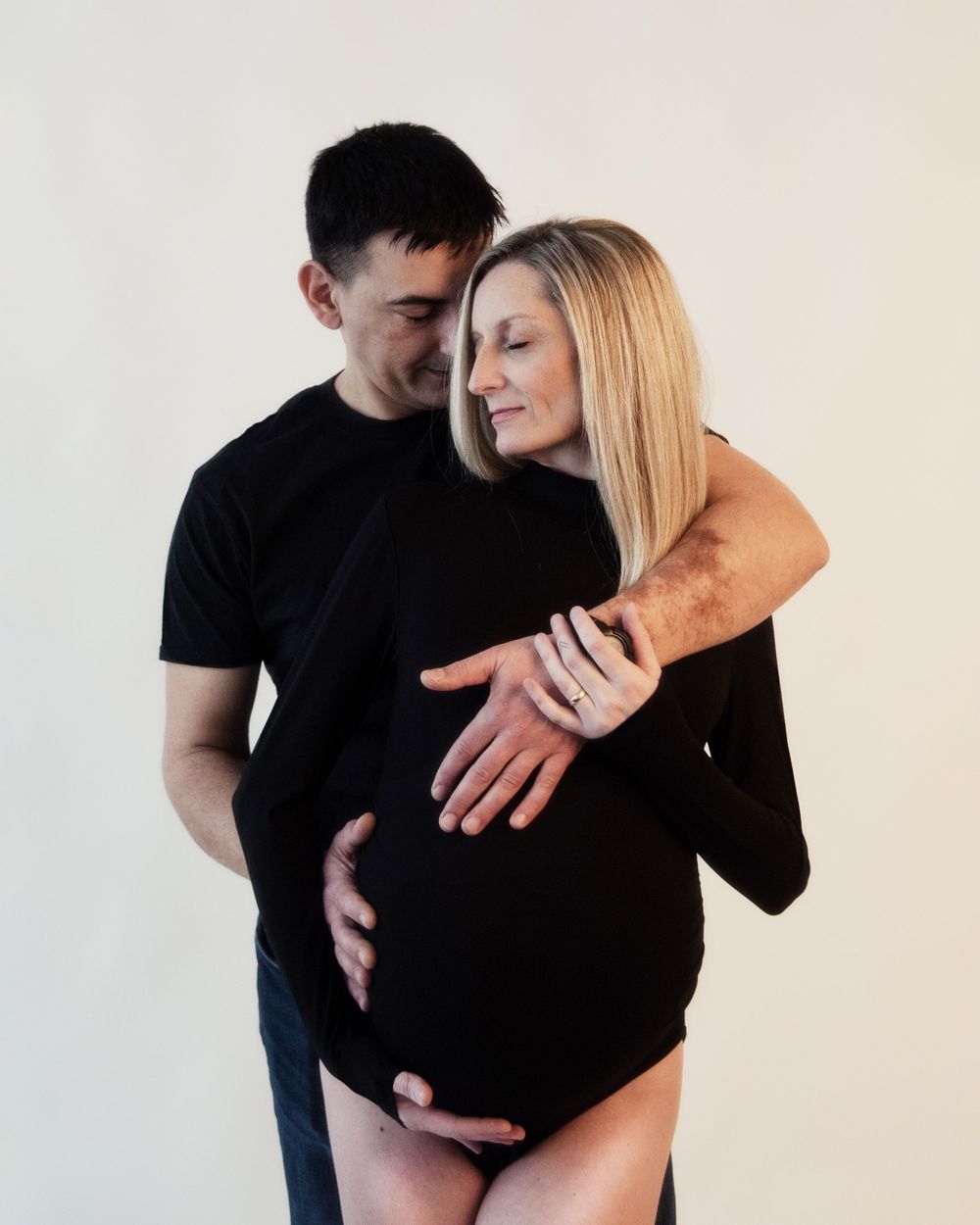Intimate maternity portrait of an expecting couple in black attire.