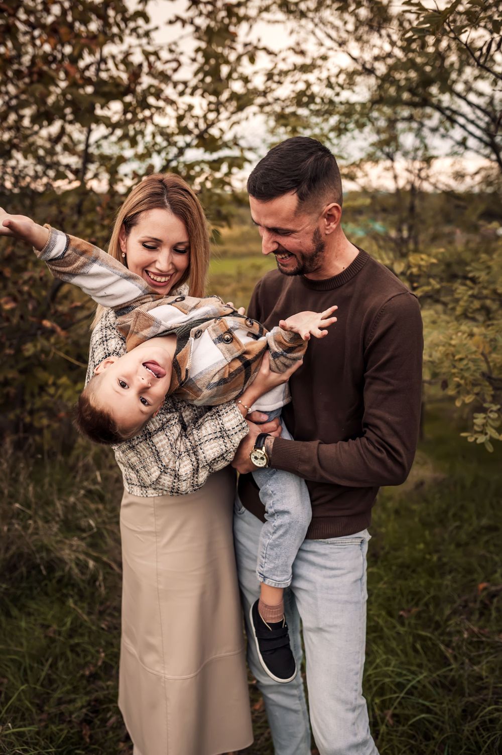 Happy family enjoying playful moment together outdoors during golden hour in natural setting.