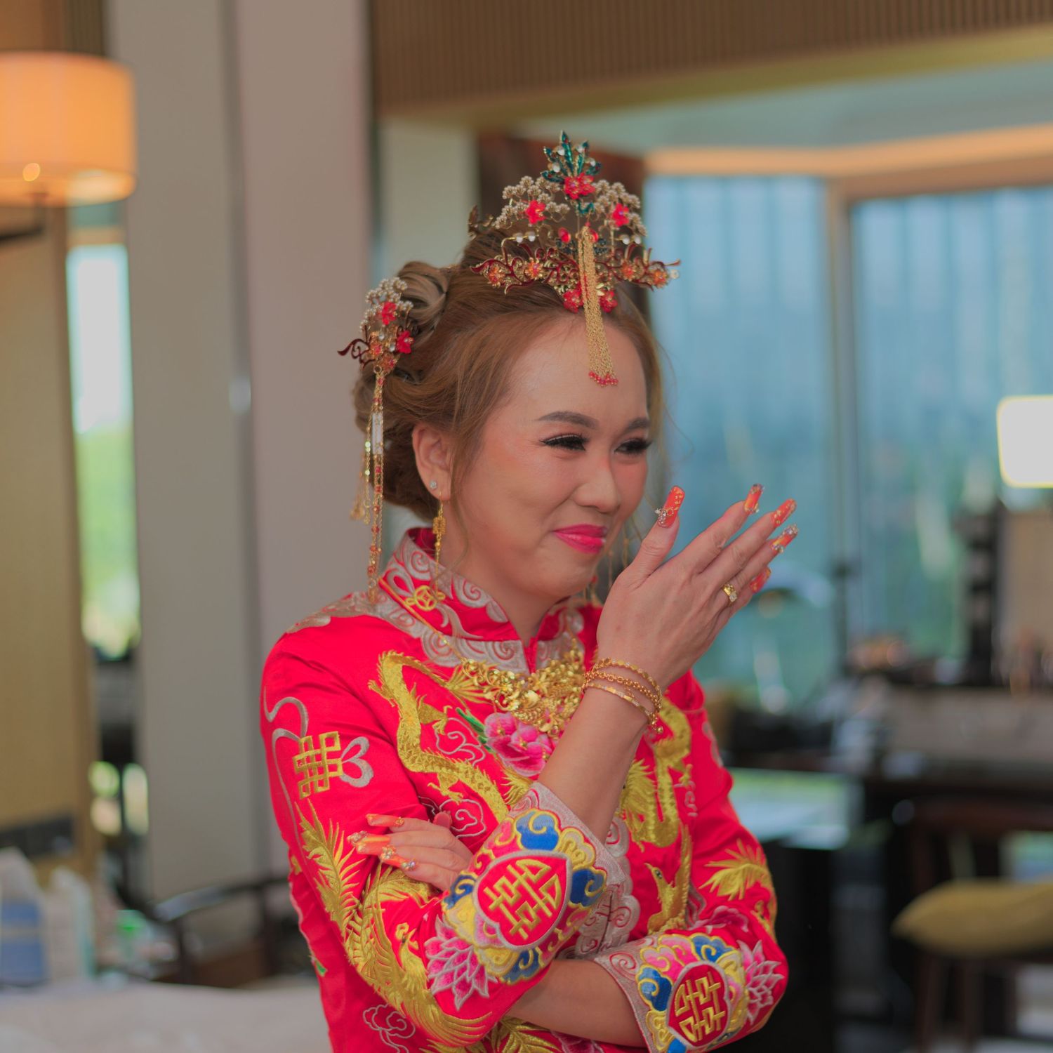 A person in red traditional Chinese attire smiles while wearing ornate hair accessories.