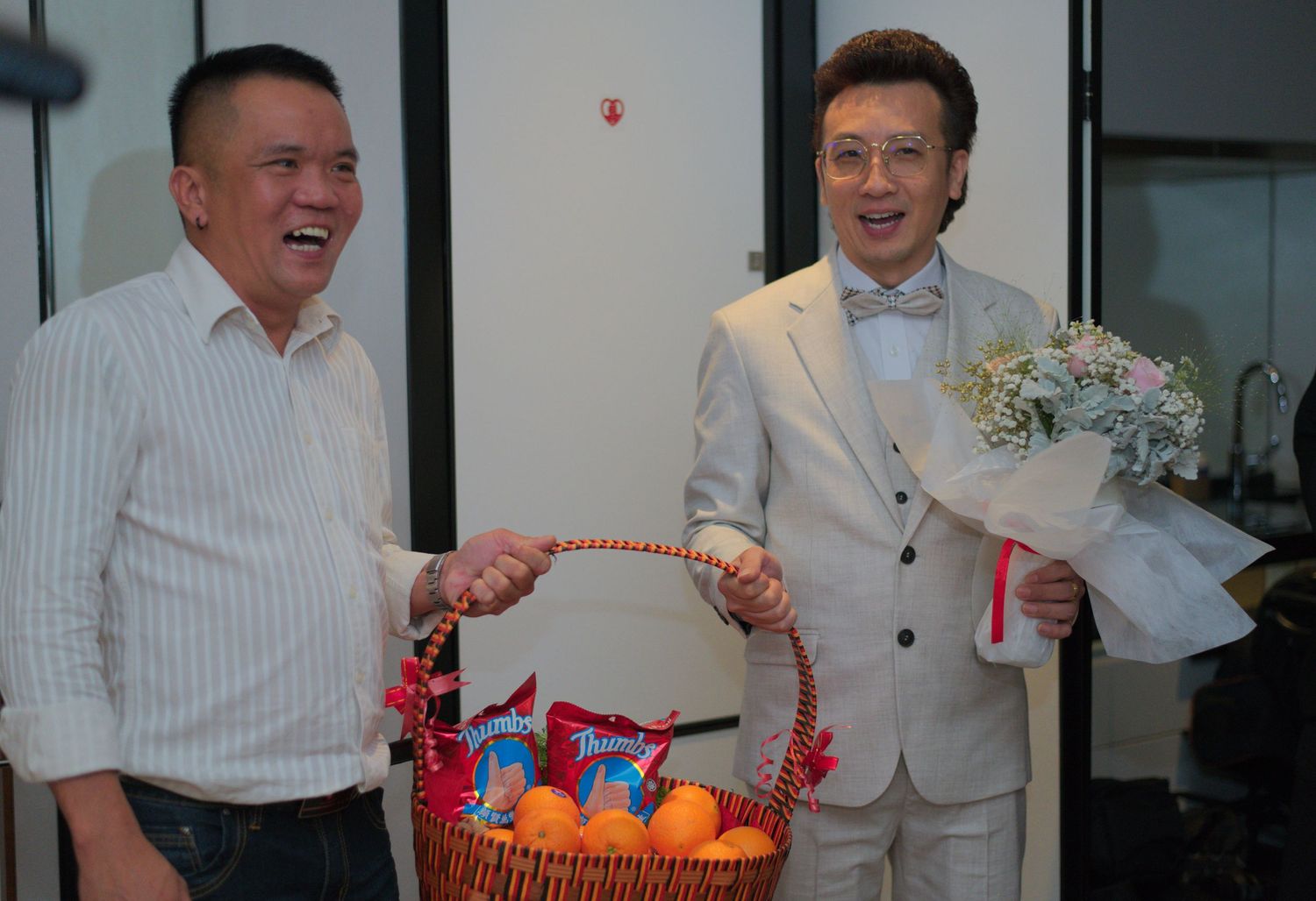 Two people exchange a gift basket during a wedding celebration.