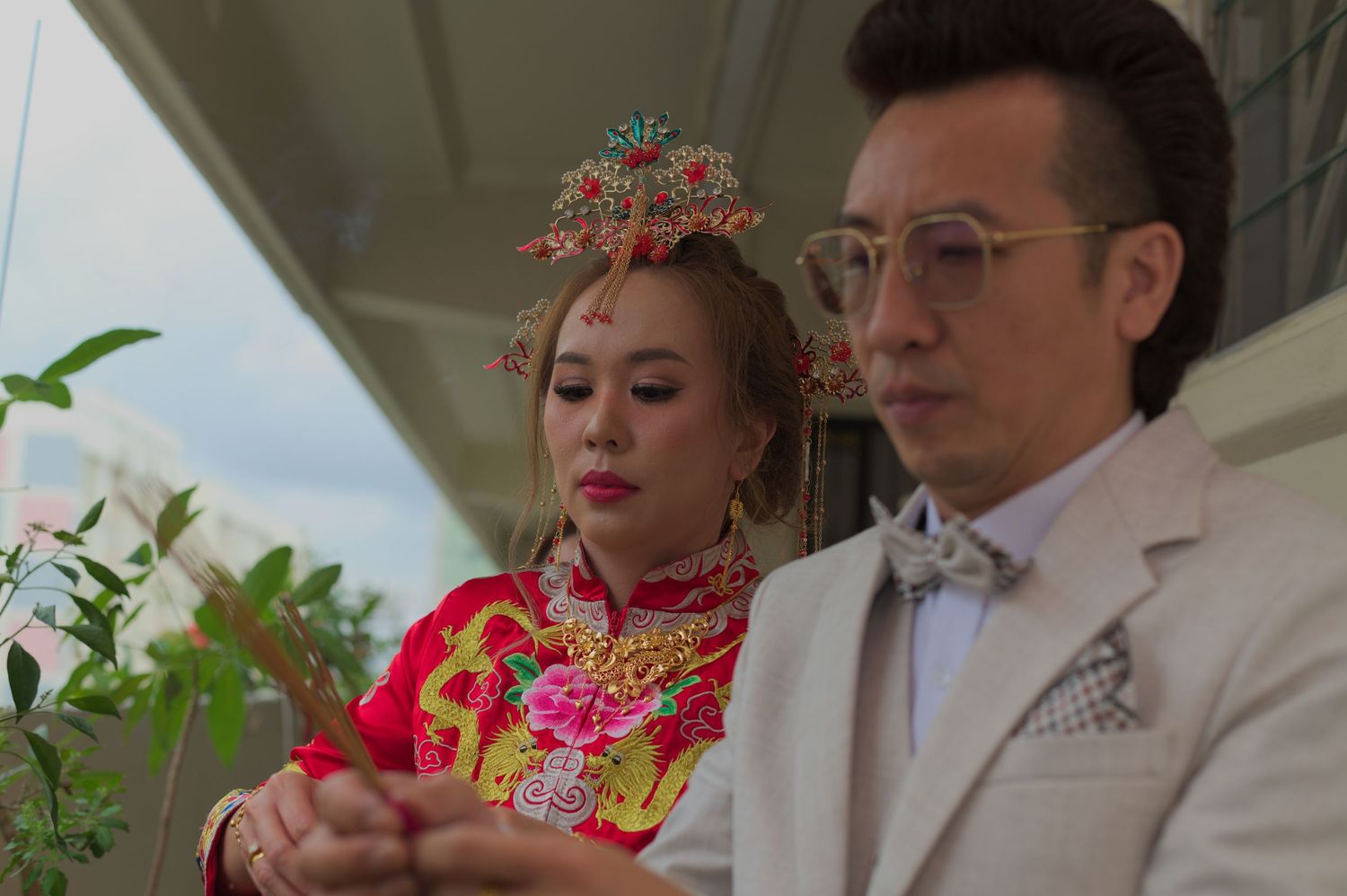A couple in formal wedding attire seated outdoors with elegant decorative elements.