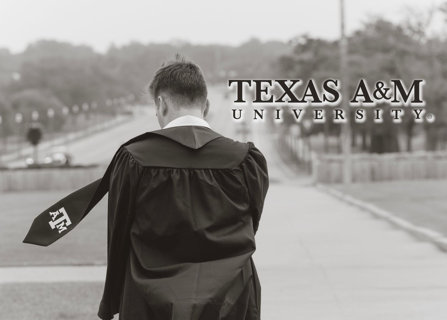 A graduate in academic regalia stands facing away from the camera with Texas A&M University text visible in the background.
