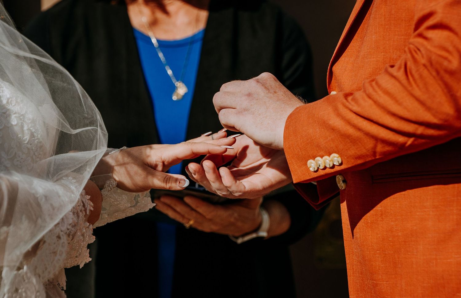 Close-up of hands exchanging rings during a wedding ceremony.